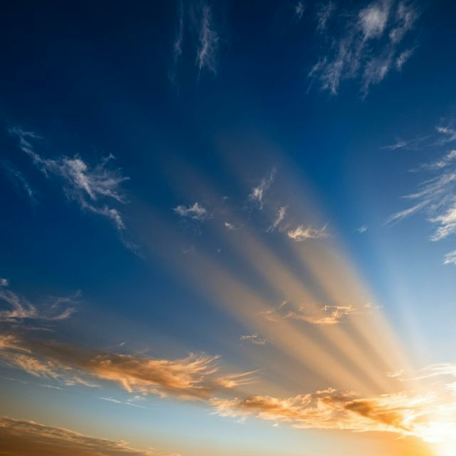 Deep blue sky gradient with subtle luminous light scattering streaks through atmosphere