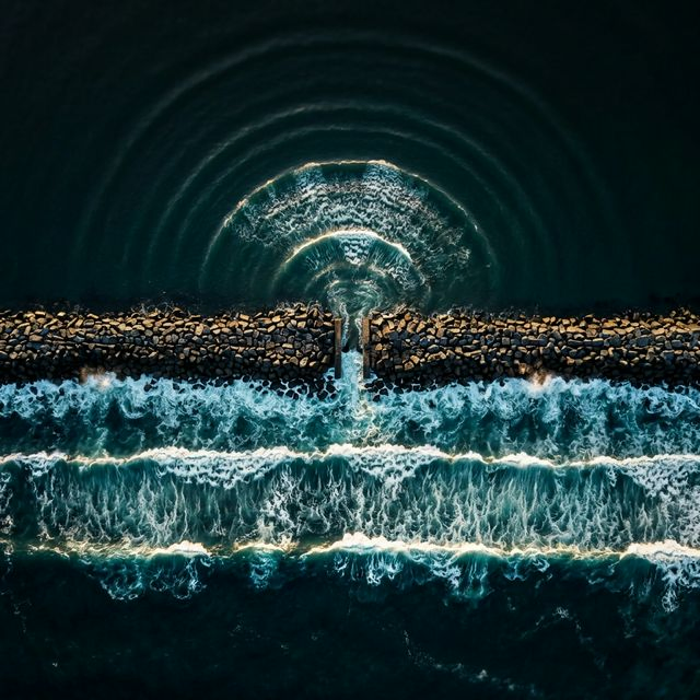 Ocean waves diffracting through a gap in a breakwater, spreading in circular arcs